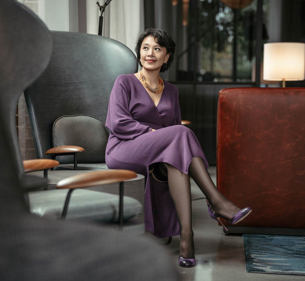 Asian business owner with short hair wearing purple dress and black sheer thigh high stockings