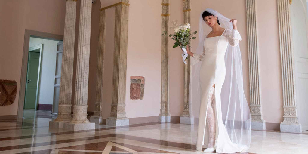 Bride wearing veil, wedding gown, and white lace thigh highs with white stilettos holding bouquet getting married.